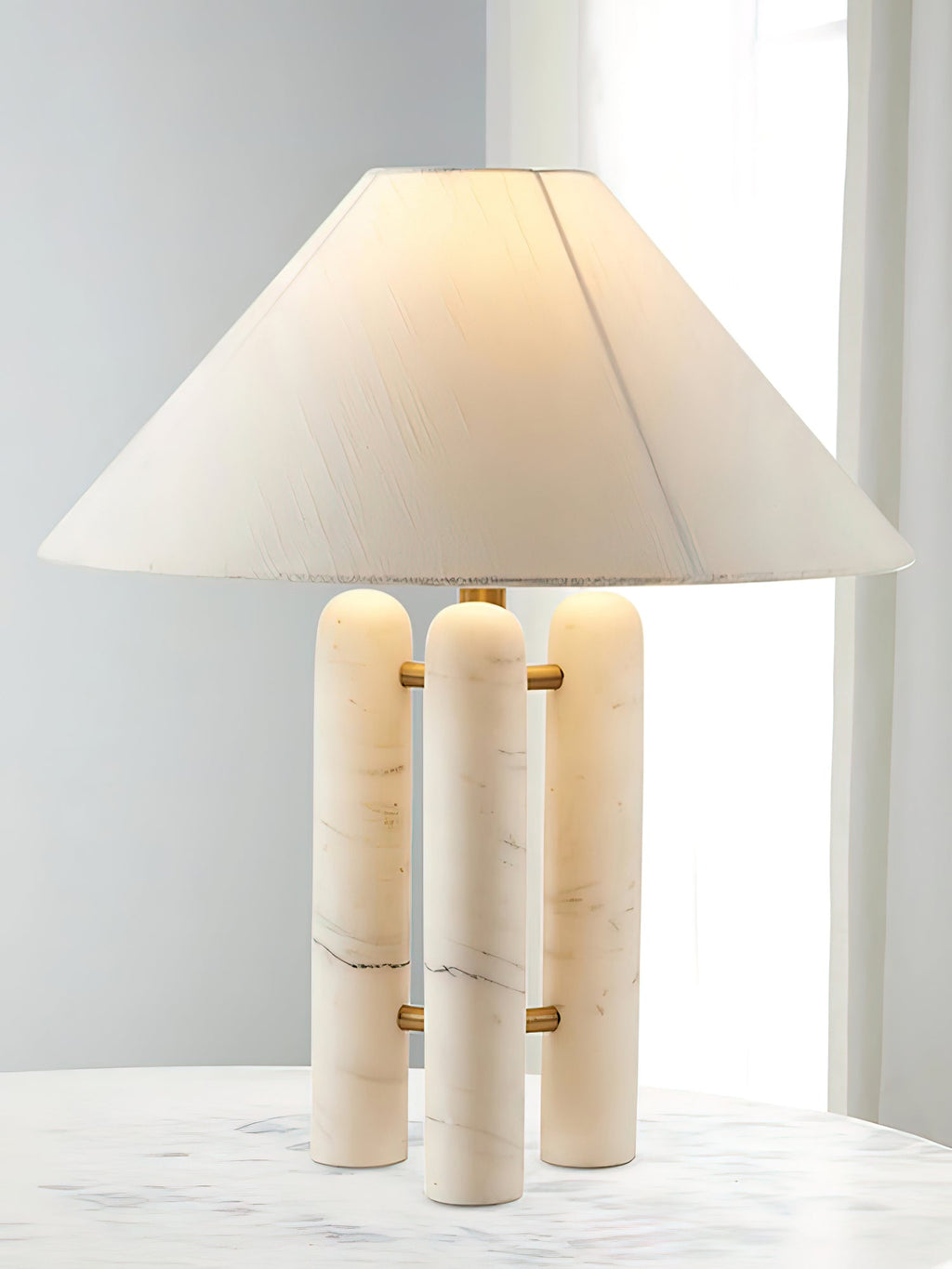 Clérachic table lamp glowing warmly on the marble table, its wide shade half-lit against the curtained window.