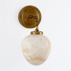Studio shot of this Clérachic wall sconce in brass finish, its teardrop alabaster shade hanging from a chain link.