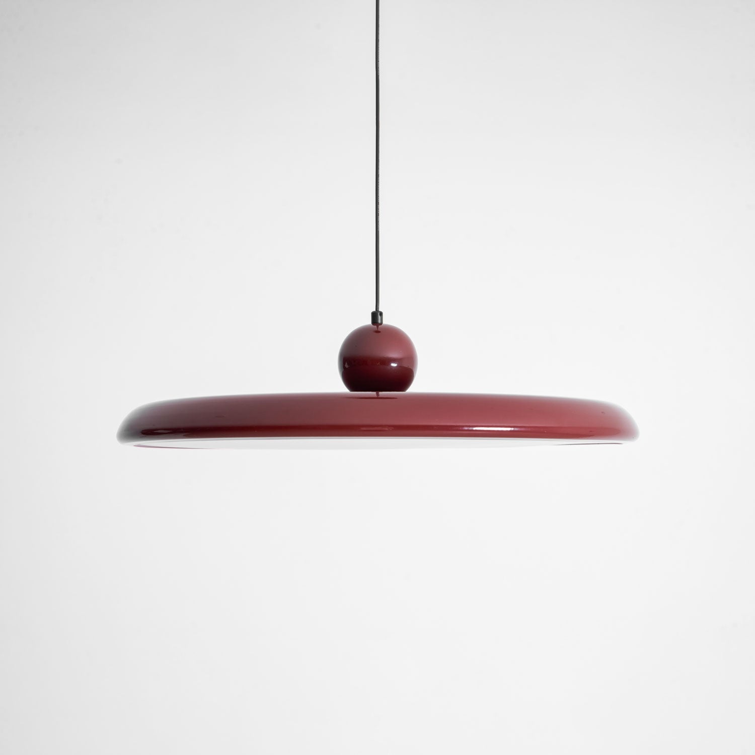 Round disc pendant light glowing softly over a table