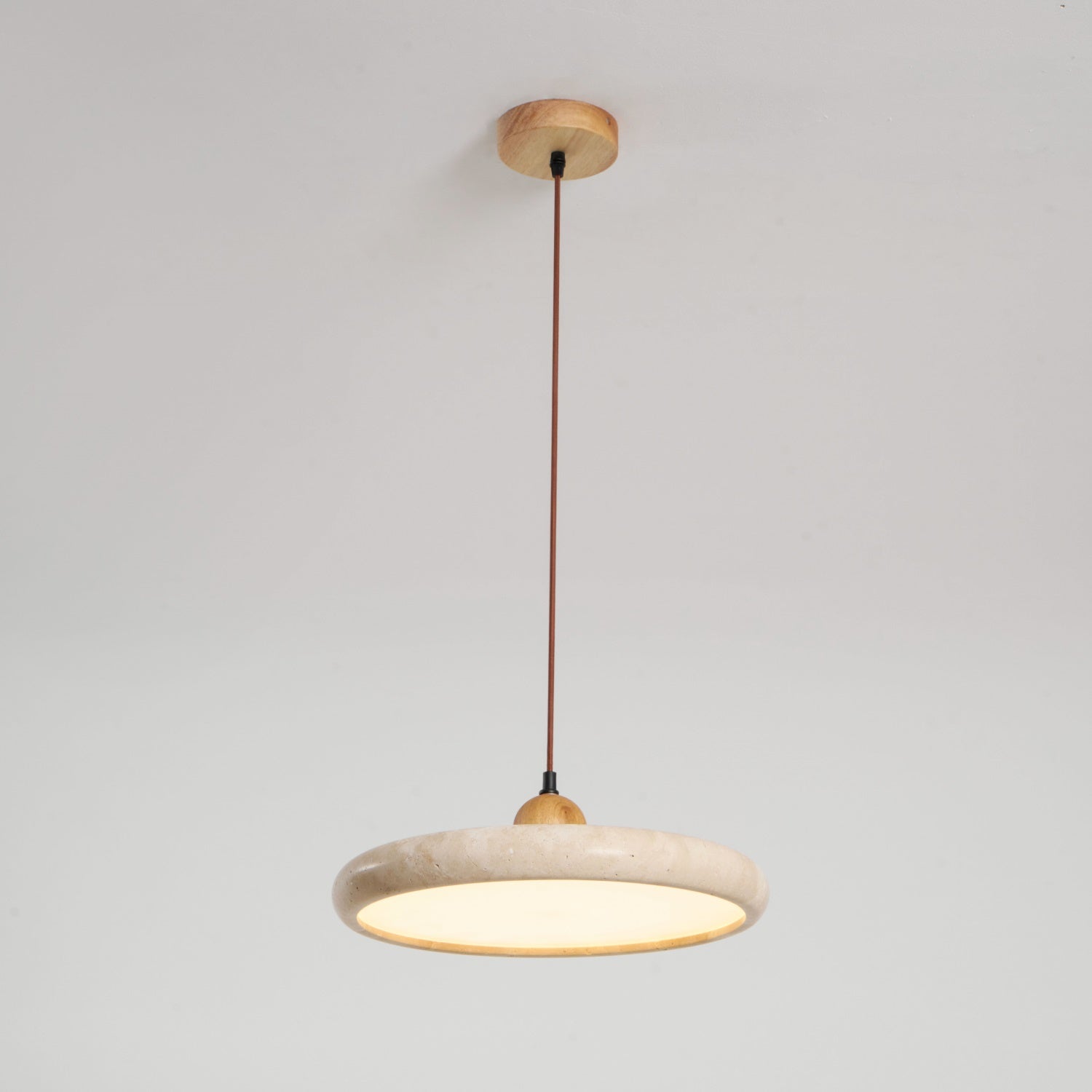Travertine stone pendant light with wood frame glowing over a table