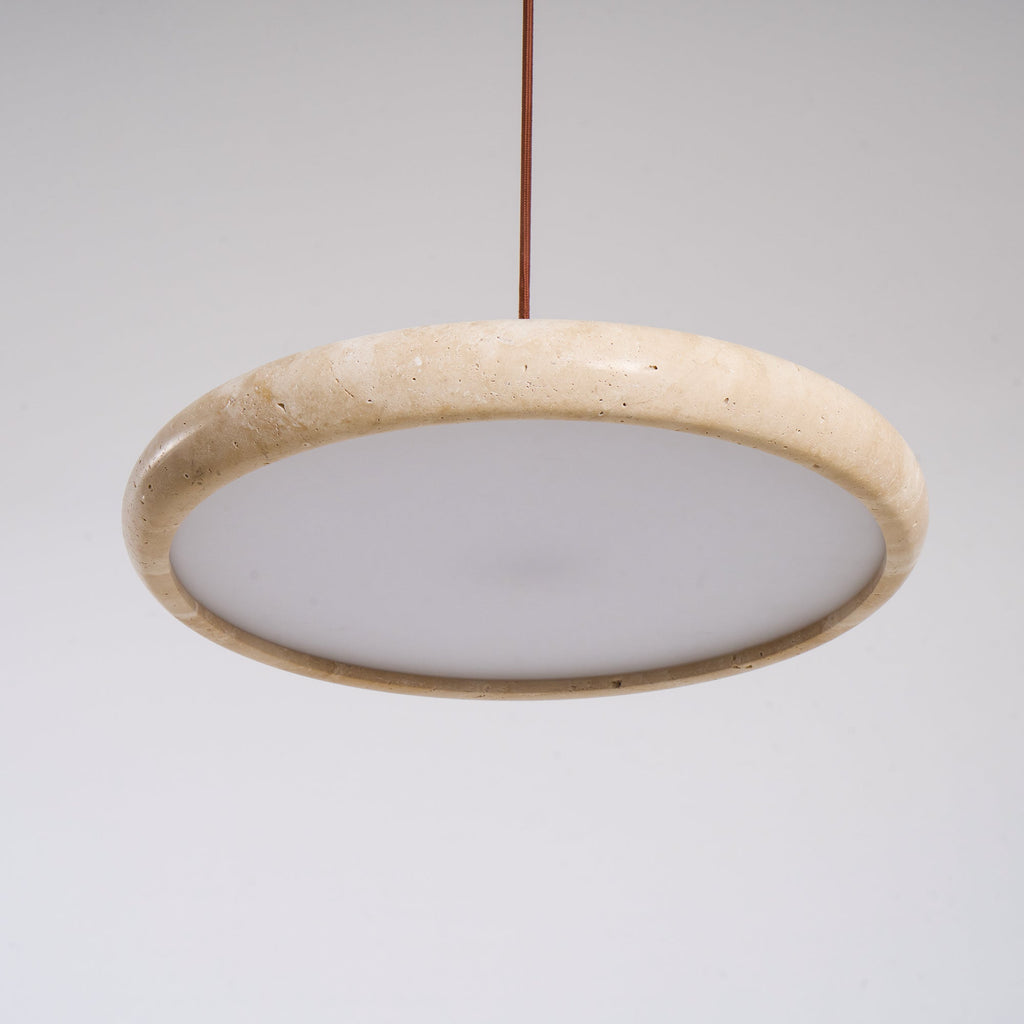 Natural travertine pendant light lit above a wooden dining table