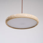 Natural travertine pendant light lit above a wooden dining table