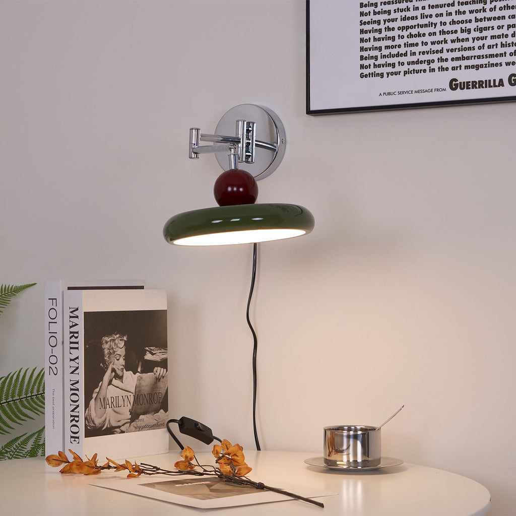 Round disc wall lamp glowing beside a styled headboard