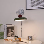 Round disc wall lamp glowing beside a styled headboard