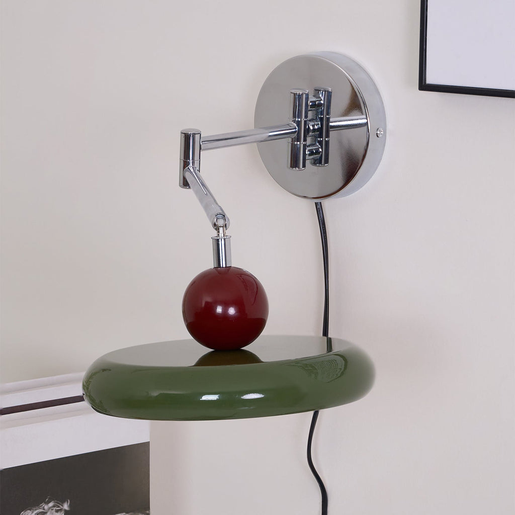 Round disc wall lamp lit warmly above a bedside table