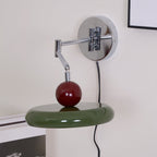 Round disc wall lamp lit warmly above a bedside table
