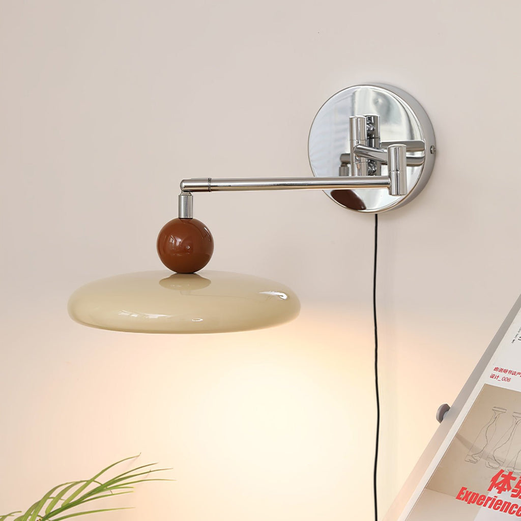 Round disc wall lamp glowing warm beside a sofa arm