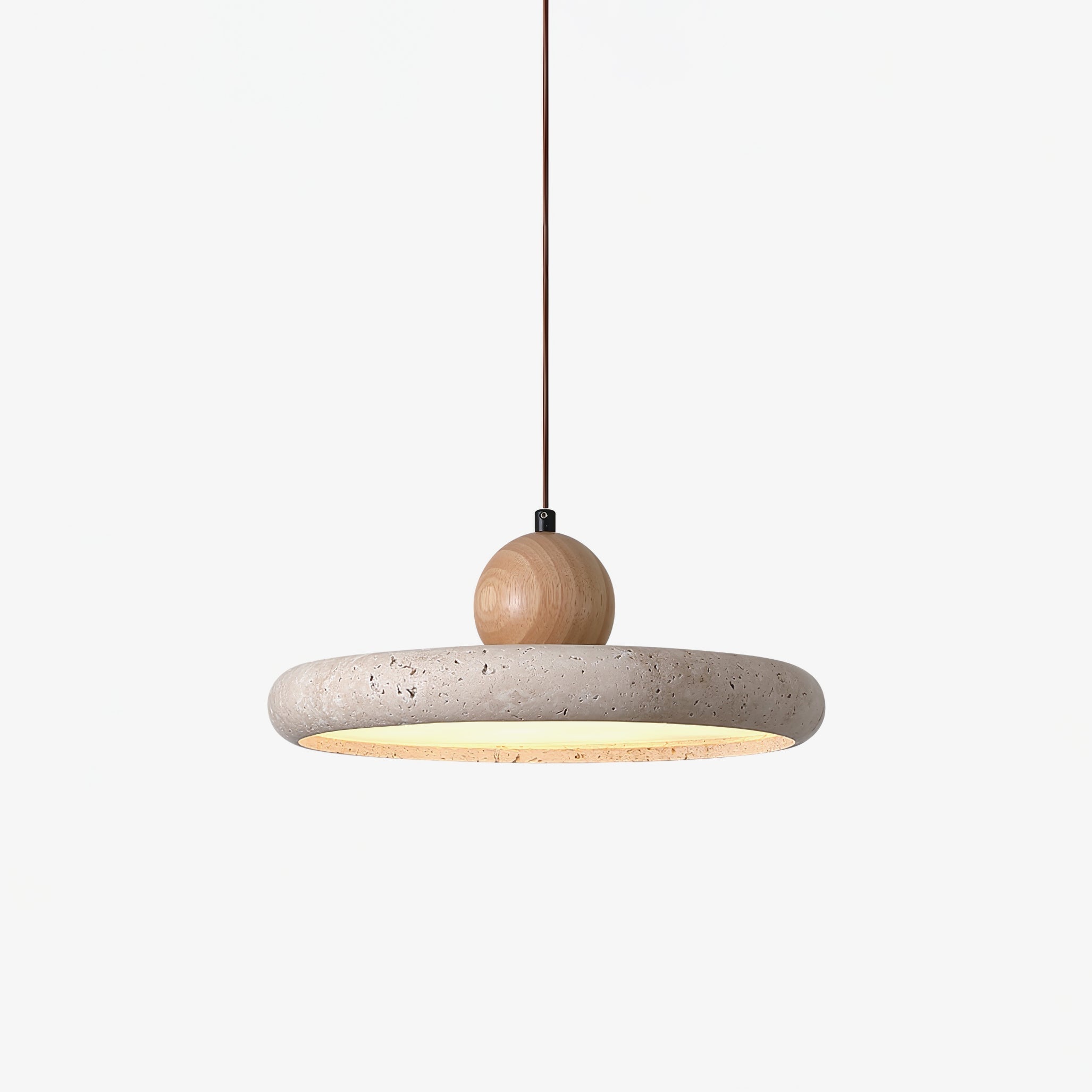 Natural travertine disc pendant light lit warmly in a living room