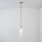 On a gold rod in a plain room beside a sheer curtain, this Clérachic pendant light glows warm white.