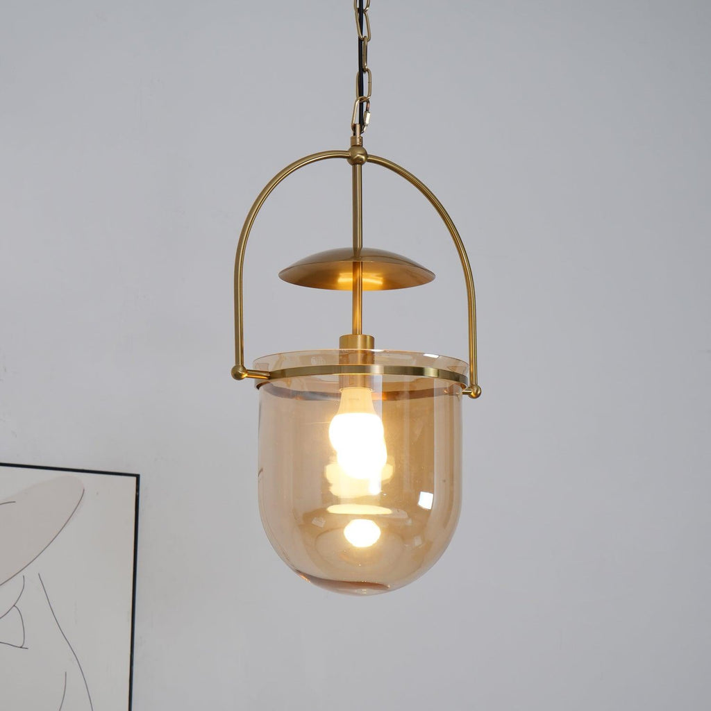 Amber glass pendant light with slim gold frame over a kitchen island