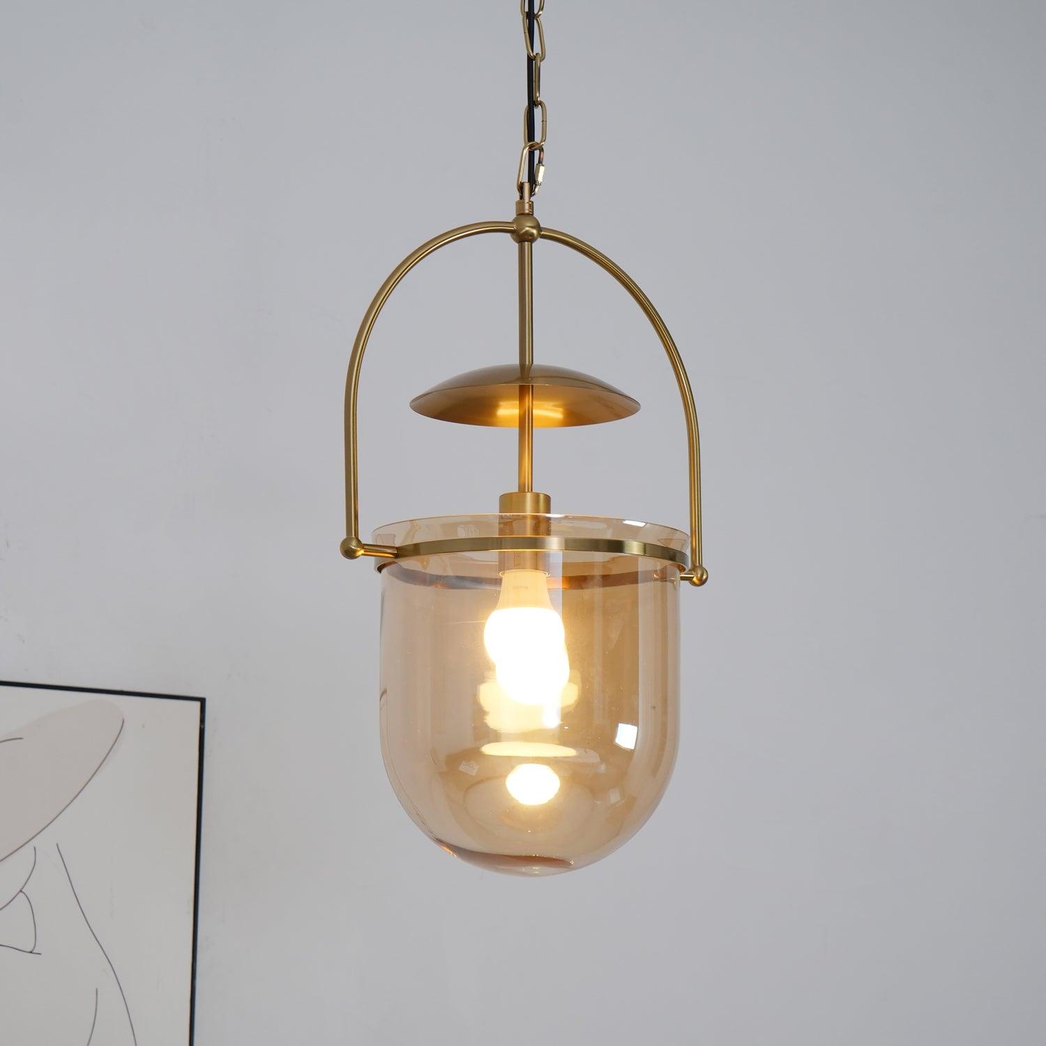 Amber glass pendant light with slim gold frame over a kitchen island