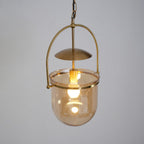 Amber glass pendant light glowing warmly over a styled table setting