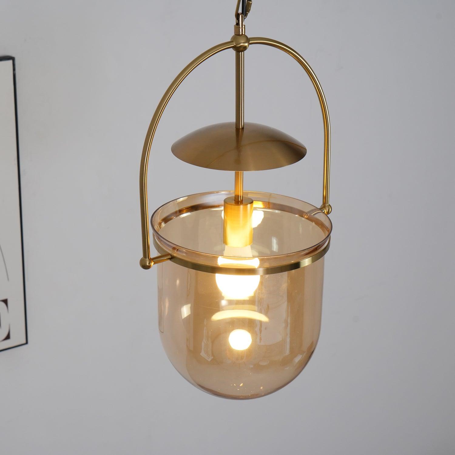 Amber glass pendant light with gold frame against a neutral wall