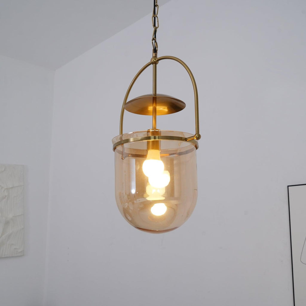 Warm lit amber glass pendant light with gold frame over a table