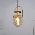 Warm lit amber glass pendant light with gold frame over a table