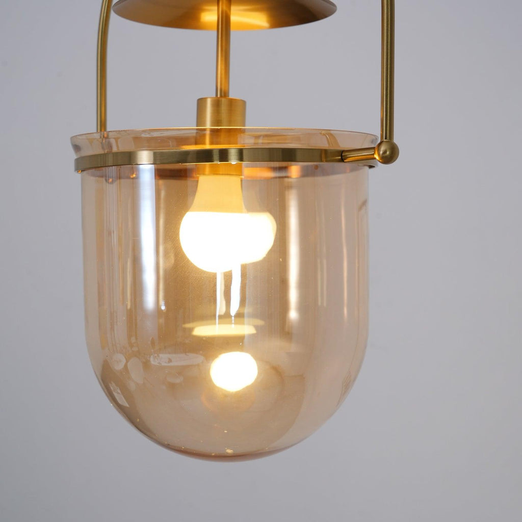 Gold frame pendant light with amber glass shade in a warm interior