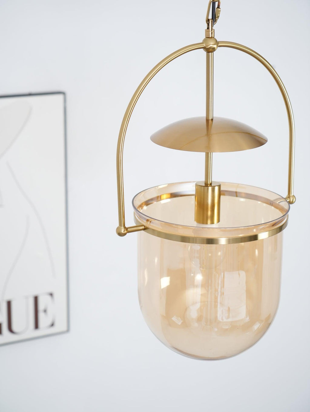 Amber glass pendant light shown from below with gold frame detail
