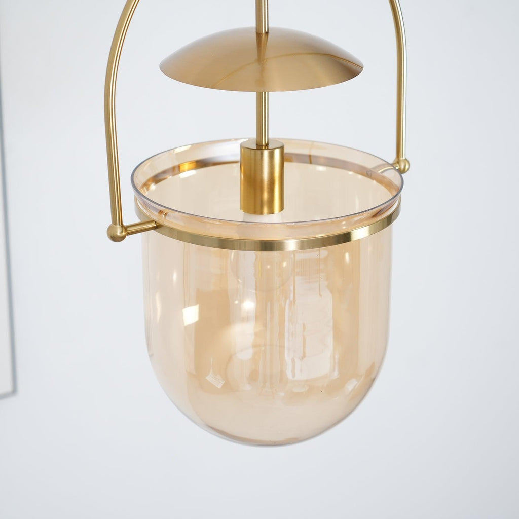 Amber glass pendant light hanging from an adjustable chain in gold