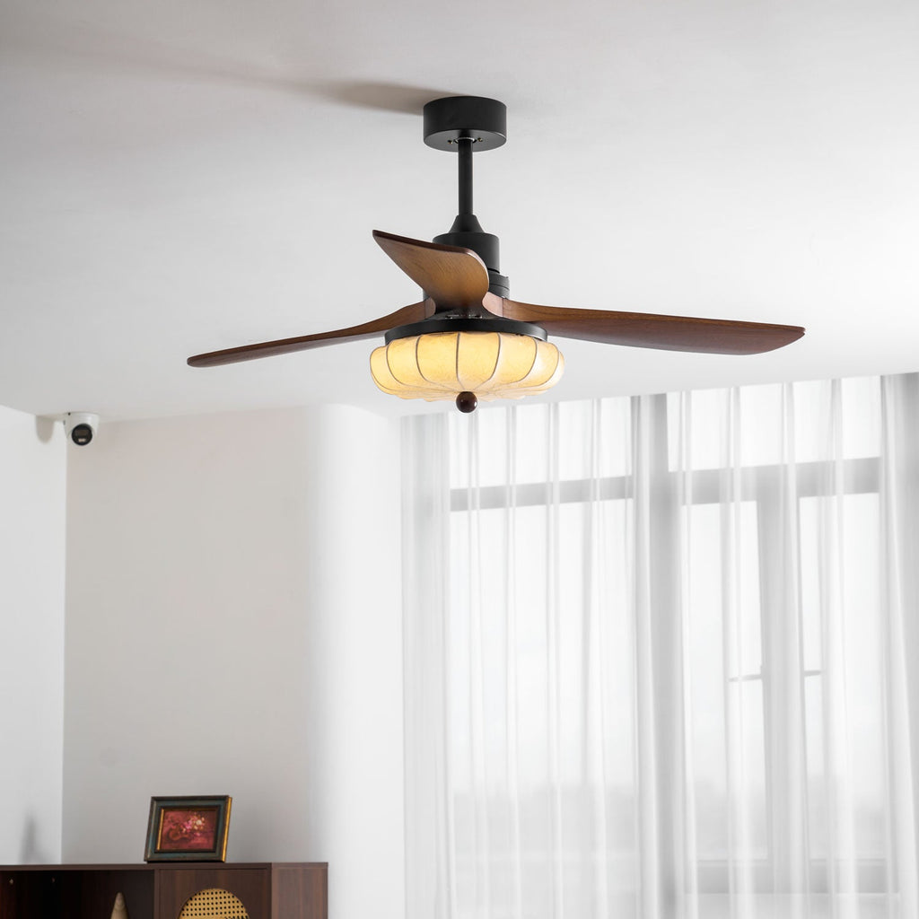 Ceiling fan with walnut blades shown spinning under the shade
