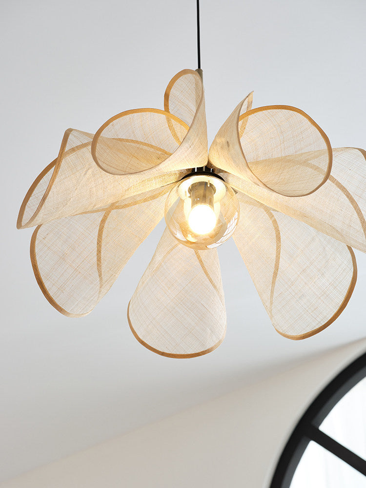 Close view from below of this Clérachic pendant's golden-trimmed beige petals fanned open around a bright bulb.
