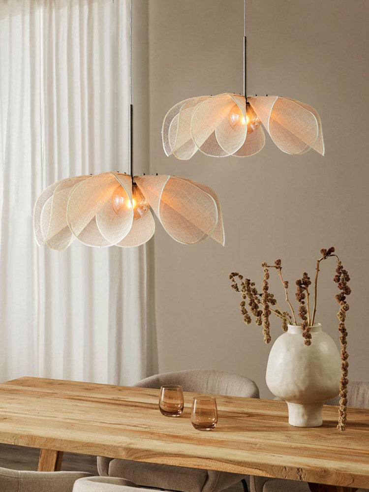 Two beige Clérachic pendants hang at different heights above a table set with a vase of dried branches.