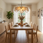 In a dining room with tall curtained windows, this Clérachic pendant's beige petals glow above a wood table.
