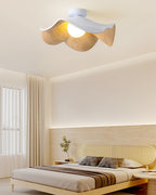 Wood-grain leaf ceiling light glowing warmly above a bedroom