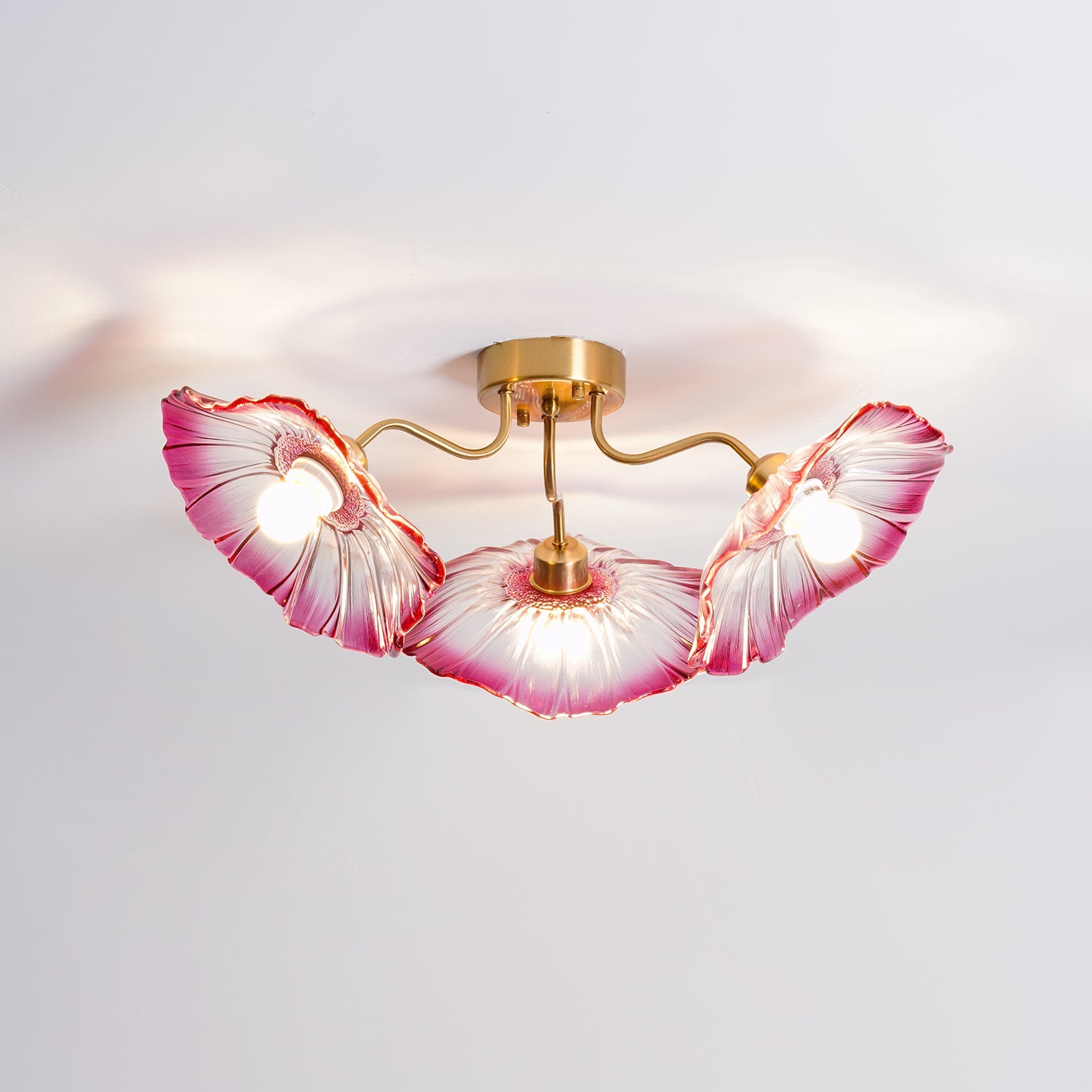 Gold ceiling light with frosted glass leaves diffusing soft light