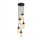 Product view of this Clérachic pendant's capsules on dark bronze rods with visible sphere joints, glowing warm.