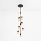 This Clérachic pendant gathers fewer alabaster capsules into a looser staggered cluster, glowing against a plain backdrop.