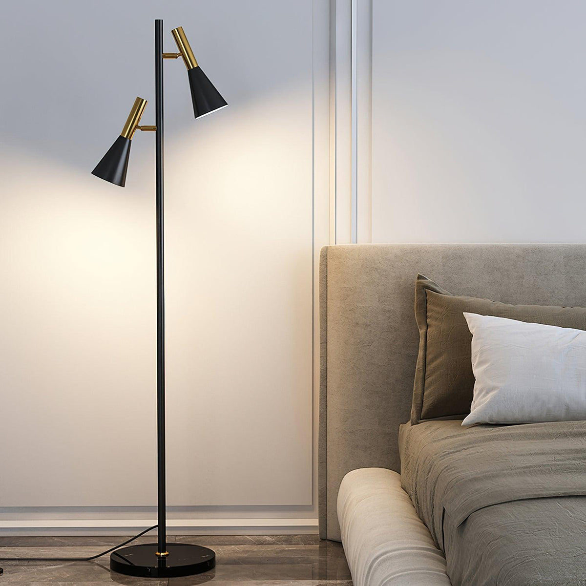 Warm light spills from a black and brass Clérachic floor lamp on its marble base against a plain bedroom wall.