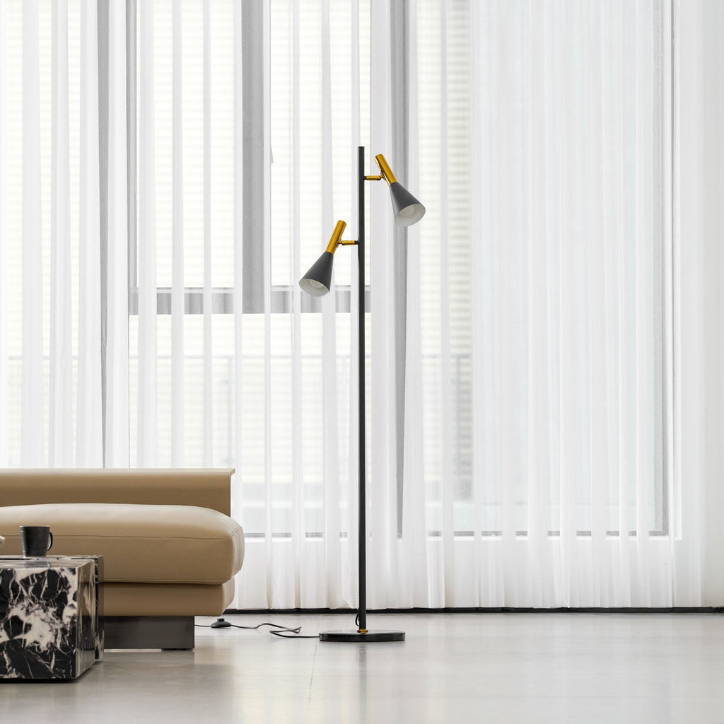 A beige ottoman and marble cube table sit near a black and brass Clérachic floor lamp, seen from further back.
