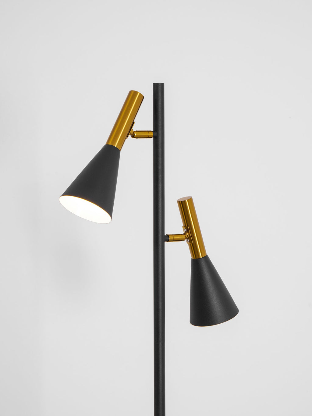 Cropped view of the two brass-necked shade heads on a black Clérachic floor lamp against a plain white wall.