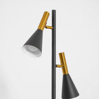Close-up of both shade heads on a Clérachic floor lamp, brass necks over black and white-lined cones on white.