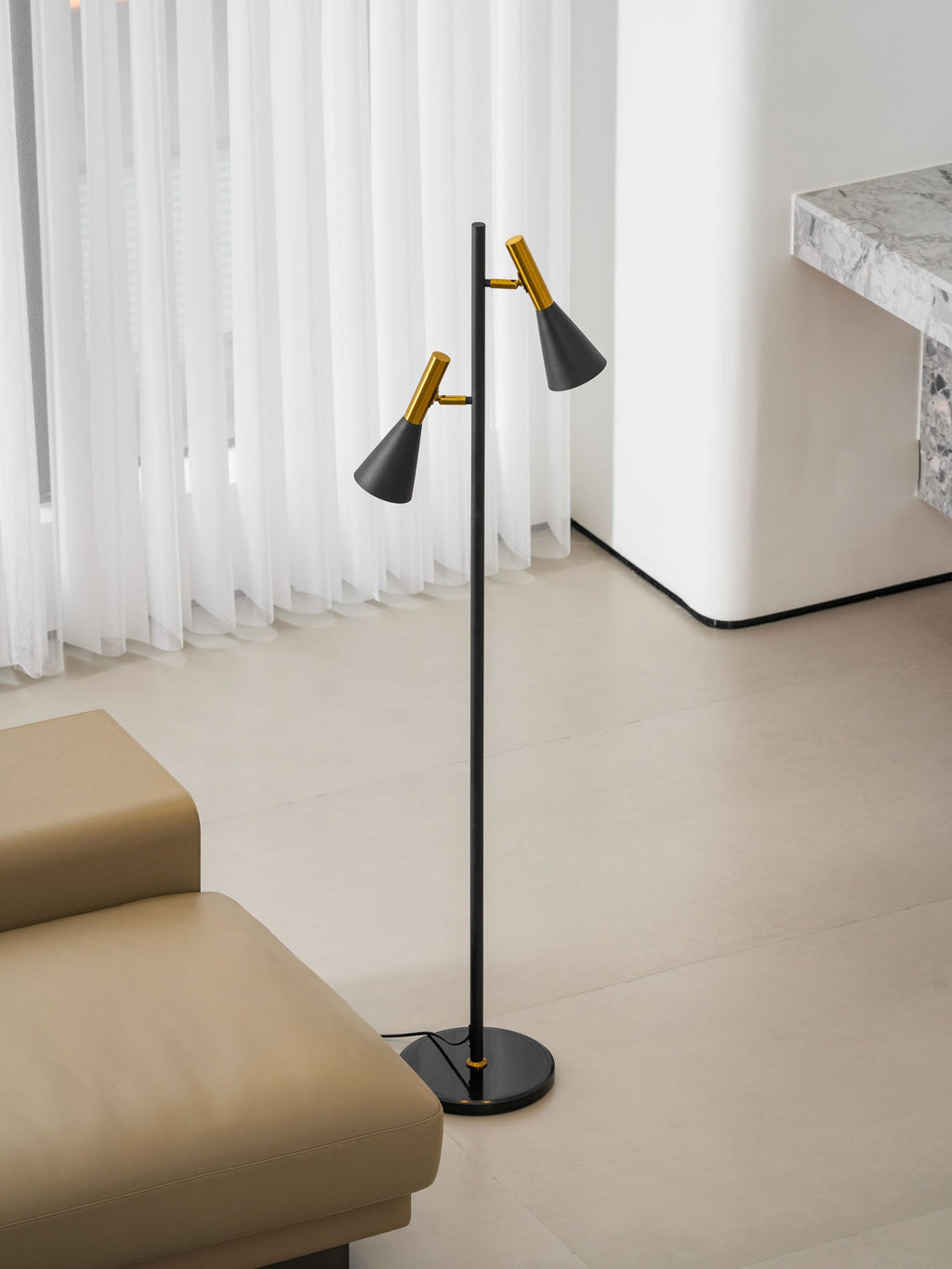 The same marble-pillared wall backs a beige leather lounge and a black and brass Clérachic floor lamp nearby.