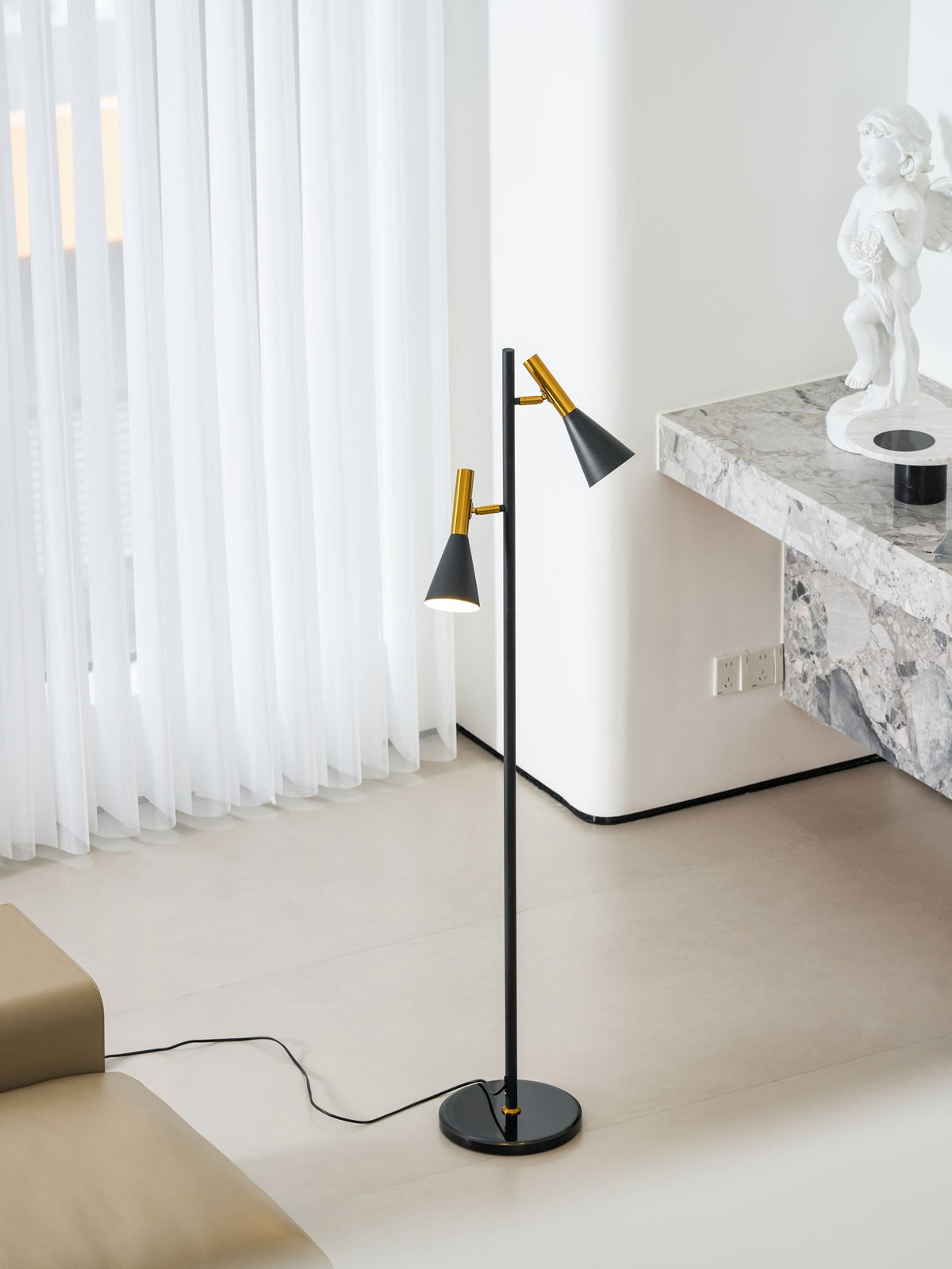 Sheer curtains glow behind a white marble pillar where a black and brass Clérachic floor lamp stands.