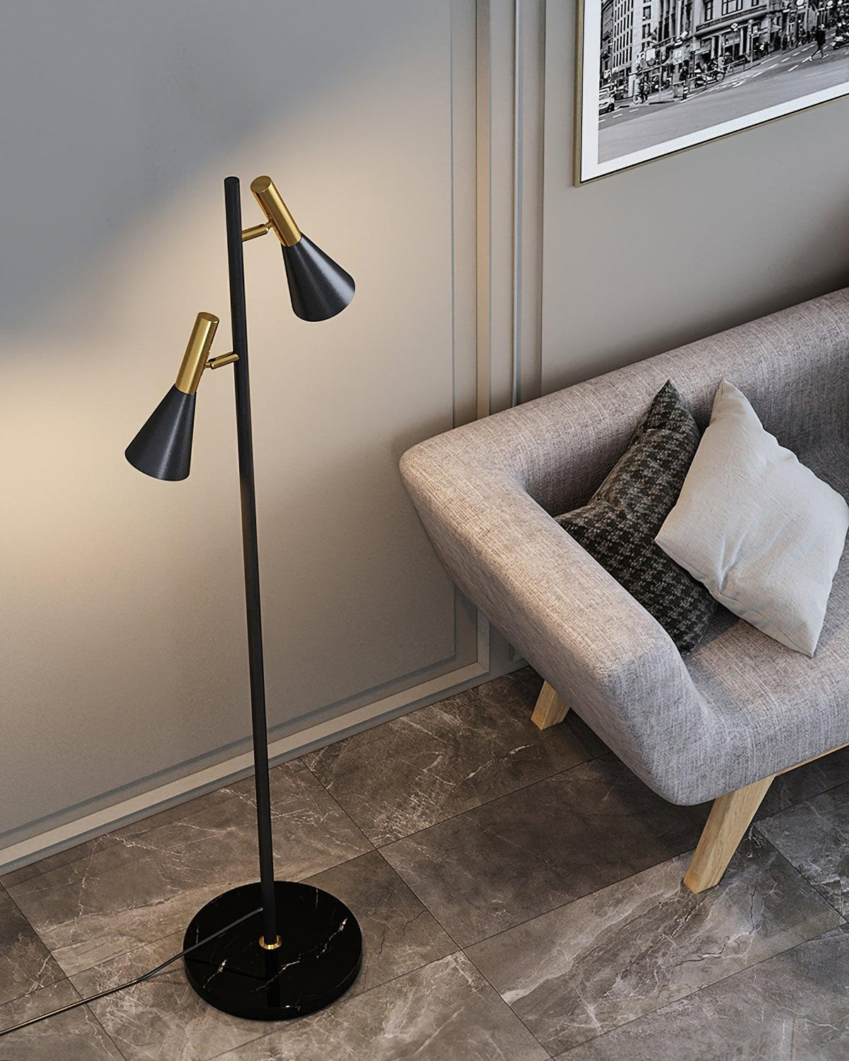 A check cushion dresses a grey sofa beside a black and brass Clérachic floor lamp lit on its black marble base.