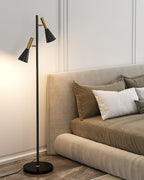 White pillows dress a beige upholstered bed beside a black and brass Clérachic floor lamp on its black marble base.
