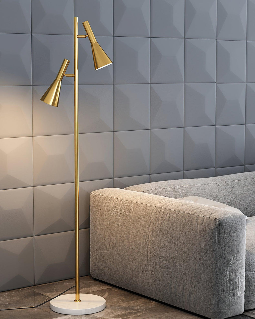 A grey geometric-tiled wall backs a grey sofa beside a brass Clérachic floor lamp on its white marble base.