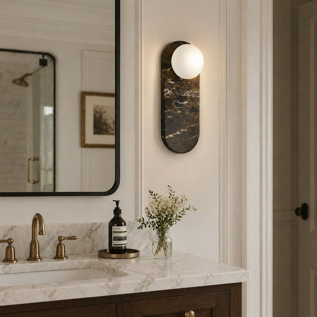 A single black marble Clérachic sconce lights the wall beside a black-framed mirror in a light wood vanity setting.