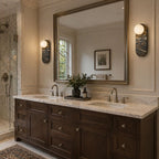 Two dark marble Clérachic sconces flank an arched mirror above a double vanity, with a walk-in shower behind.