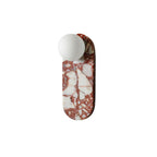 Straight-on studio shot of the Clérachic sconce in red-and-white marble on a white background, shade unlit.