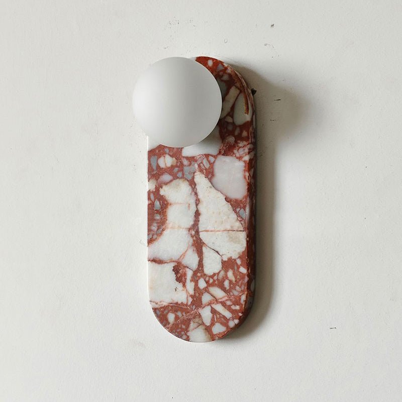 Close-up of a red-and-white fractured marble Clérachic sconce against a soft beige wall, its shade unlit.
