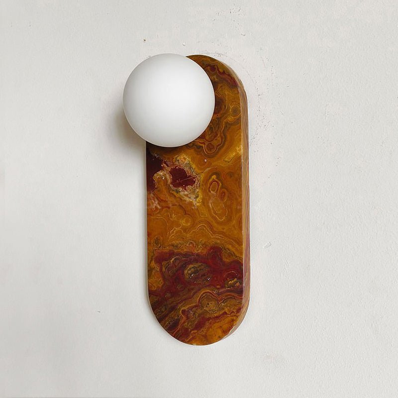 Close-up of the amber and rust-swirled marble finish on the Clérachic sconce, shade unlit against a plain wall.
