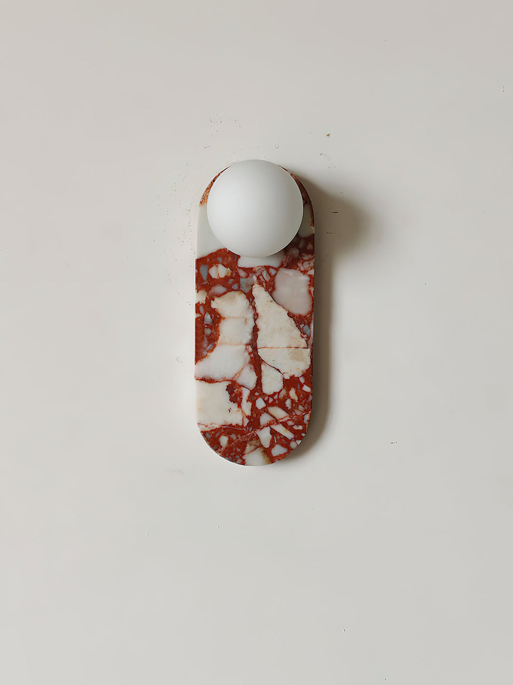 Studio shot of the red-and-white marble Clérachic sconce on a pure white background, glass shade unlit.