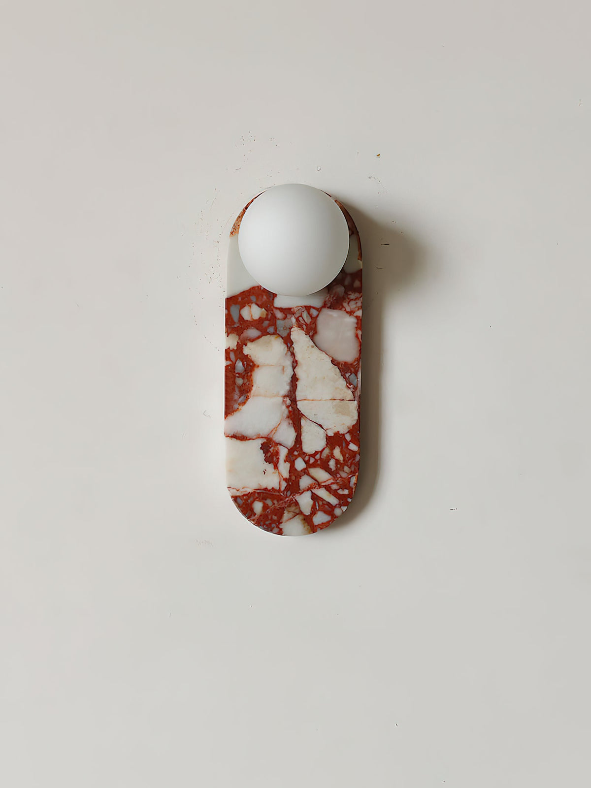 Studio shot of the red-and-white marble Clérachic sconce on a pure white background, glass shade unlit.