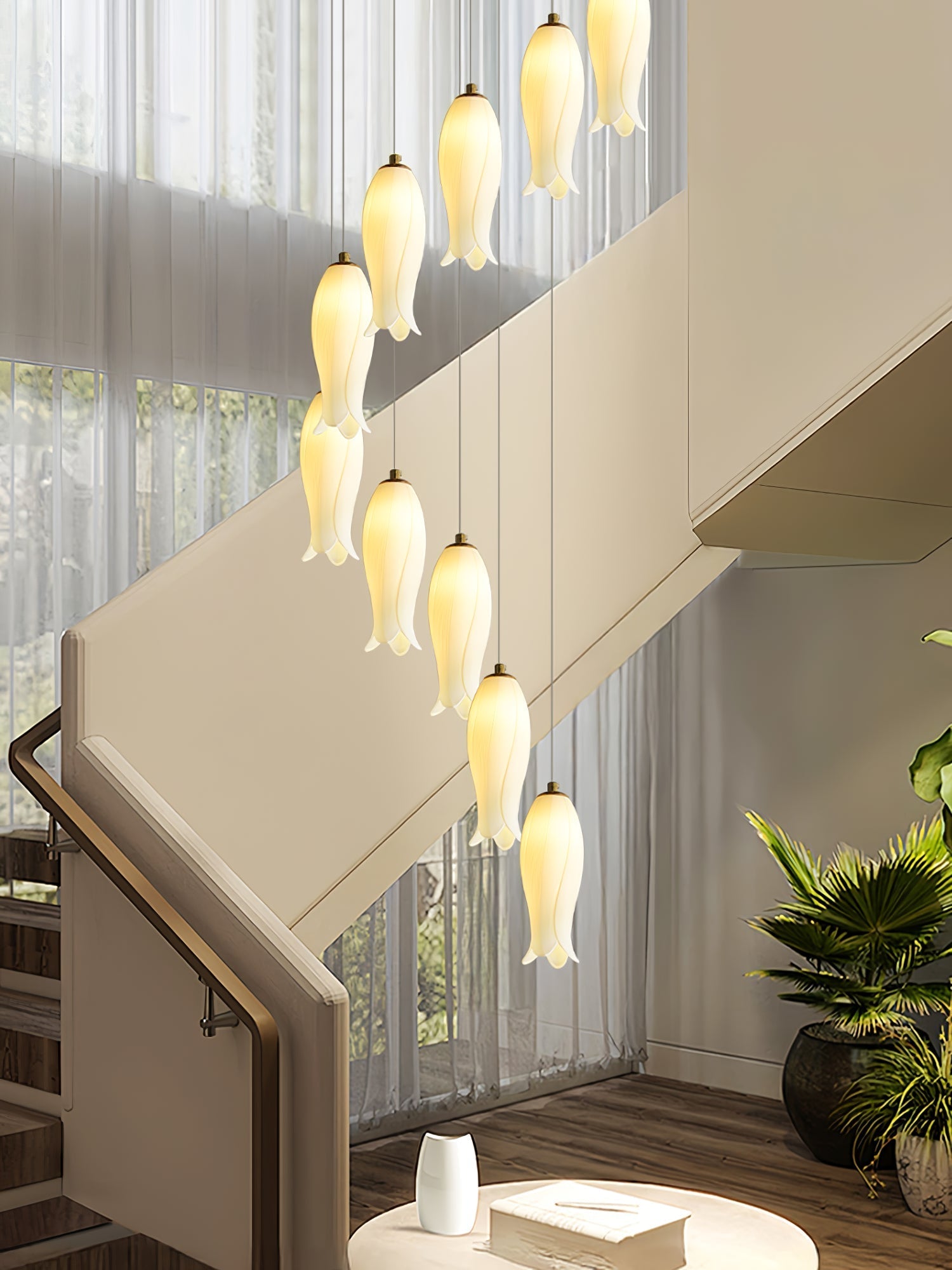 Close view of the ceramic shades lit beside a staircase, sheer curtains and a potted palm behind