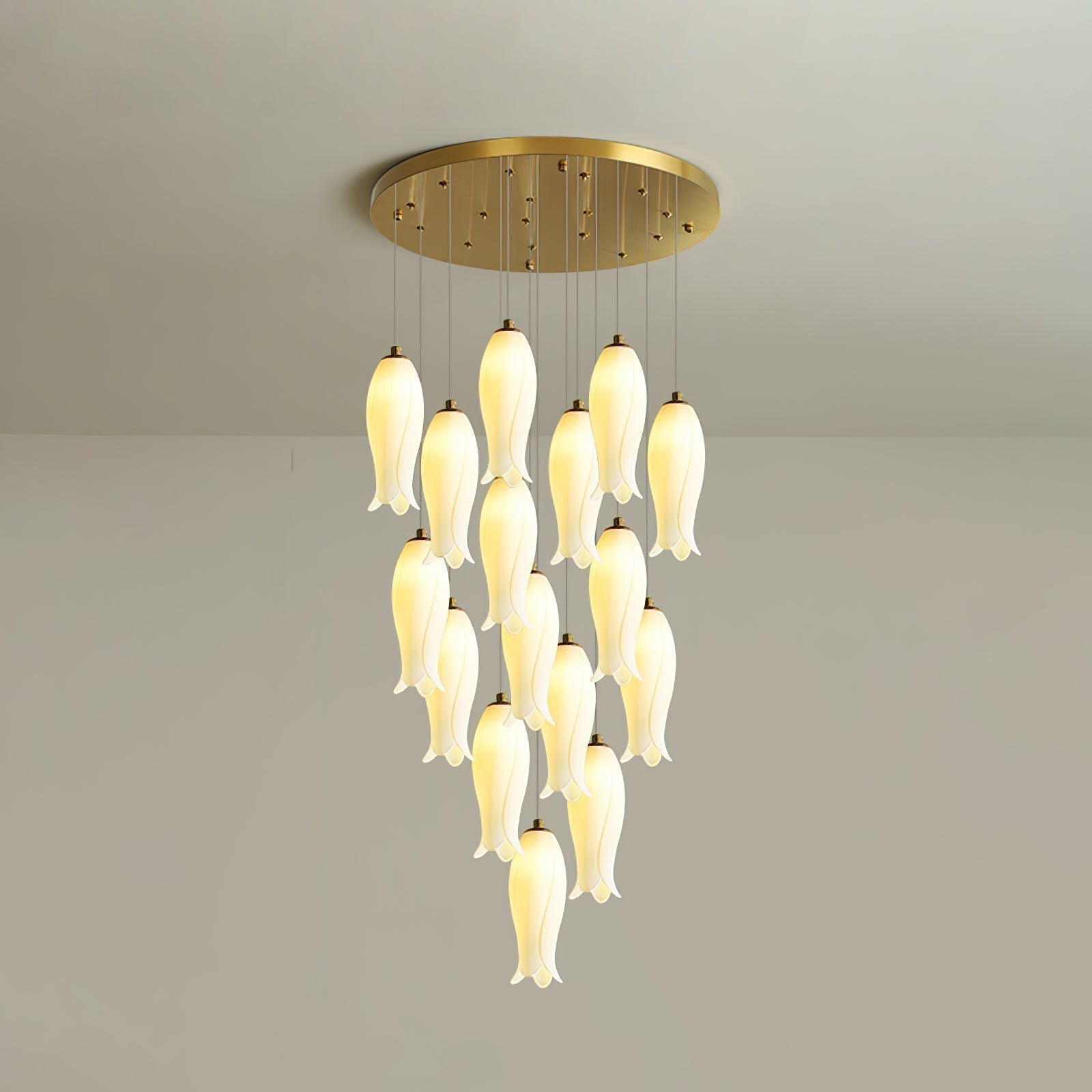 Sixteen-light Sylirion lit against a grey studio wall, gold ceiling plate visible above the cluster