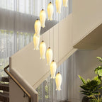 Detail view of individual ceramic shades, each on its own cable, lit beside a curtained stairwell