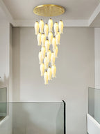 Sylirion lit above a glass balustrade in a plain white stairwell, shades tapering to a single tip